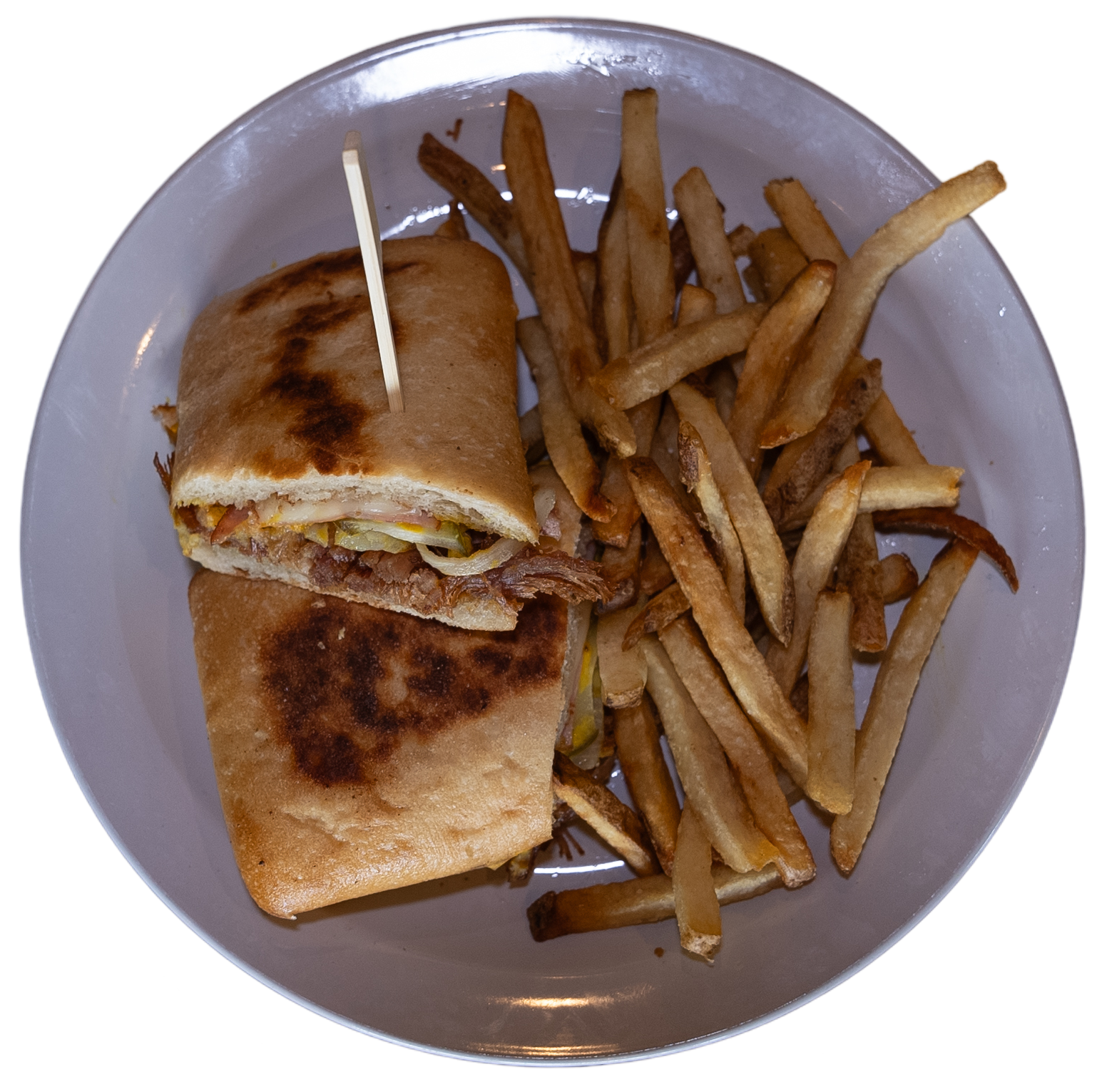 A plate with a sandwich cut in half, secured with a toothpick, next to a serving of French fries.