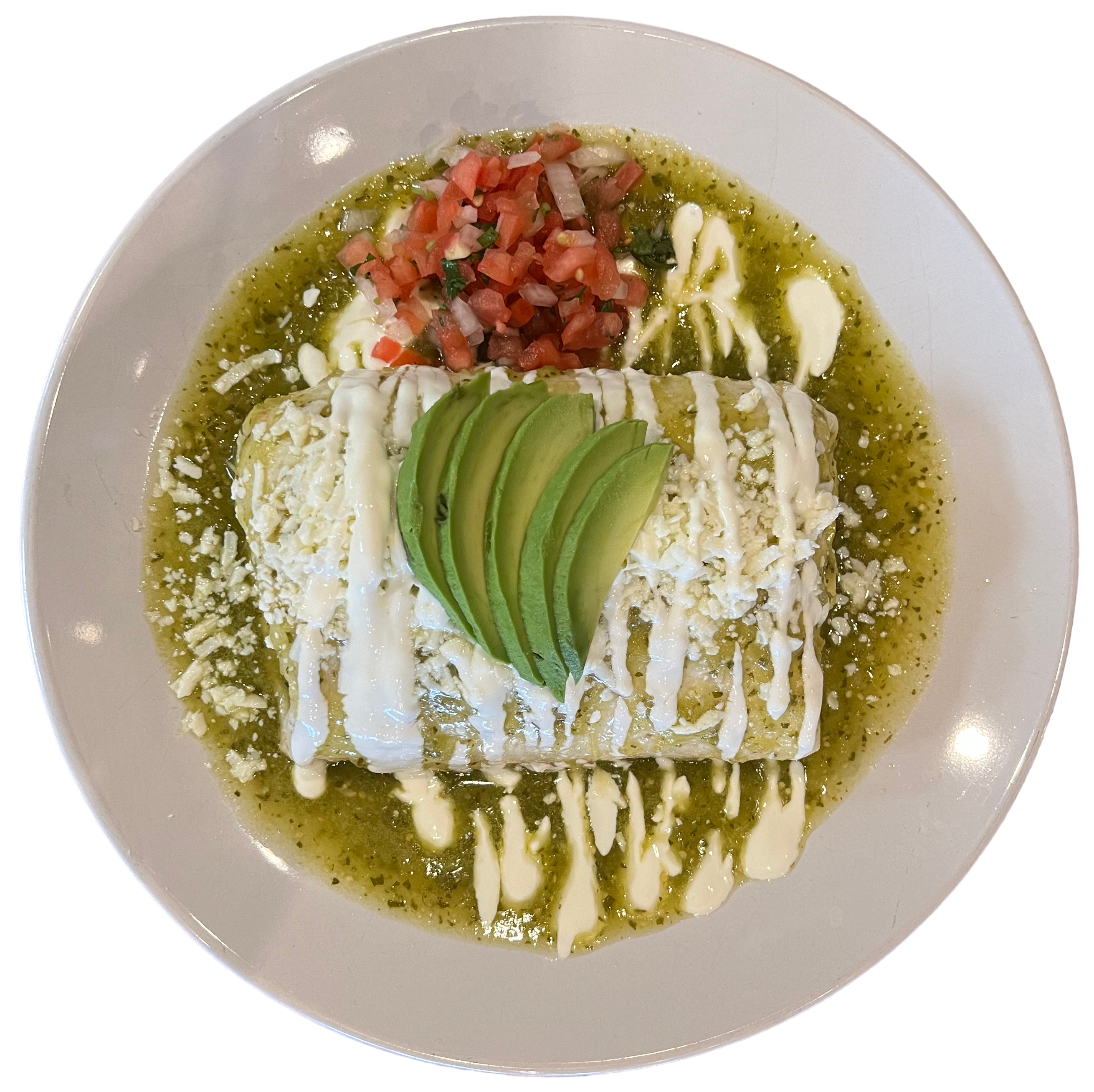 A plate with an enchilada covered in green sauce, topped with avocado slices, crema, and cheese, accompanied by a side of diced tomatoes and onions.